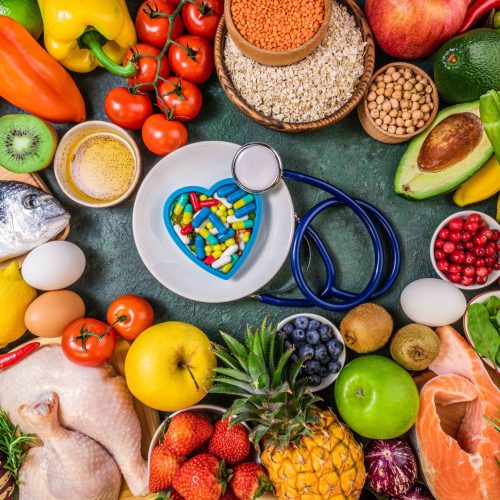 Background of healthy food. Fresh fruits, vegetables, meat and fish on table. Food to boost immunity. Choice healthy food or medicine pills concept. Top view, copy space